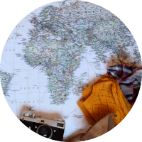 A map with a camera, sweater and scarf laying on top. 