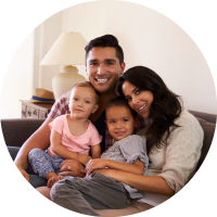 A young family cuddles together on a couch. 