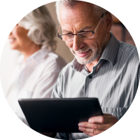 An elderly man looks at a tablet